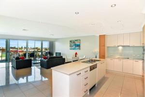 uma cozinha com armários brancos e uma sala de estar em Gallery Resort Style Penthouse No 13 em Victor Harbor