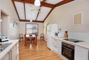 a kitchen with white appliances and a table in it at Goolwa Blue Escape - Beach Spacious Wi-fi in Goolwa