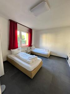 two beds in a room with a window and red curtains at 7 Zimmer Haus in Kaiserslautern in Kaiserslautern