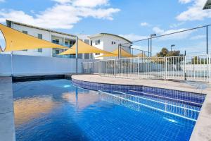 una piscina junto a una valla y un edificio en Gallery Resort Style Penthouse No 13, en Victor Harbor