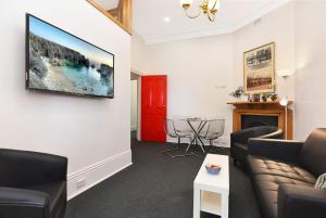 uma sala de estar com um sofá e uma televisão na parede em Cecil Mansions Wi-fi Parking Central Location em Adelaide
