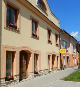 ein Gebäude mit Blumen in den Fenstern und einem gelben Schild in der Unterkunft Penzión Max Kežmarok in Kežmarok
