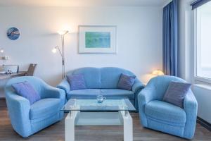 sala de estar con 2 sillas azules y mesa en Haus Atlantic, FeWo 505 en Döse