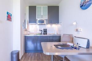 una pequeña cocina con armarios azules y una mesa en Haus Atlantic, FeWo 505 en Döse