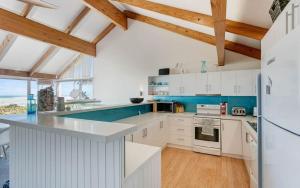 una cocina con armarios blancos y detalles azules en Glass House By The Ocean Wi-fi, en Middleton