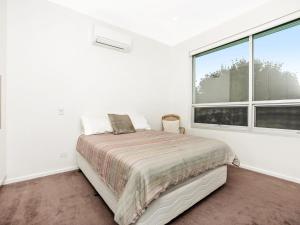 a white bedroom with a bed and a large window at Muse On The Murray Pet-friendly in Wellington
