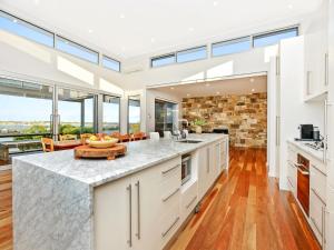 an open kitchen with white cabinets and a large window at Muse On The Murray Pet-friendly in Wellington