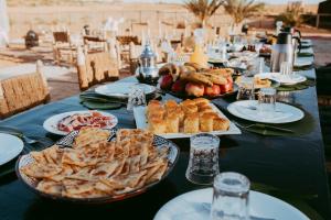 a long table with plates of food on it at Kam Kam Dunes in Merzouga