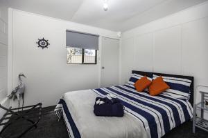 ein Schlafzimmer mit einem Bett mit einer blau-weißen gestreiften Decke in der Unterkunft Riverglades Murray Bridge in Murray Bridge