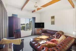 ein Wohnzimmer mit einem Ledersofa und einem TV in der Unterkunft Riverglades Murray Bridge in Murray Bridge