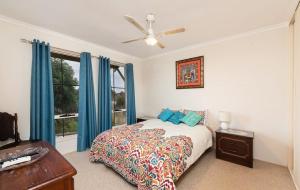 um quarto com uma cama com cortinas azuis e uma janela em Milang Lakefront Retreat em Milang