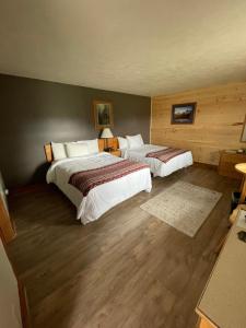 Spillover Motel and Inn في Stratton: سريرين في غرفة الفندق مع أرضيات خشبية