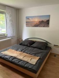 ein Bett in einem Schlafzimmer mit einem Bild an der Wand in der Unterkunft Ferienappartement am Meer in Wilhelmshaven