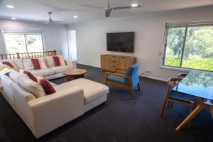 a living room with a white couch and a tv at Sandy Pool Shack - Pet Friendly in Seacliff