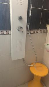 La salle de bains est pourvue d'une douche avec un tabouret jaune. dans l'établissement Laila, à Creil