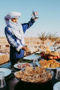 a woman standing in front of a table with food at Kam Kam Dunes in Merzouga