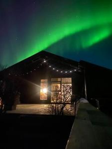Ein Gebäude mit grüner Aurora am Himmel in der Unterkunft Heart of the Golden Circle with Hot Tub in Selfoss