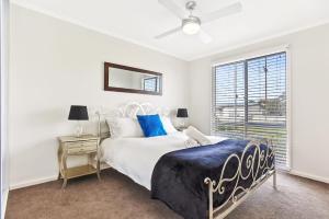 een witte slaapkamer met een bed en een raam bij Sa Holiday House 'dunes Views On Simpson' in Goolwa