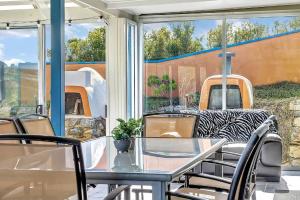 a glass table and chairs on a patio at The Darling Of Marina - A Hilltop And Sea Getaway in Wirrina Cove