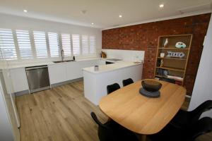 a kitchen with a wooden table and a brick wall at Southern Sands' Beachfront Apartment in Port Elliot