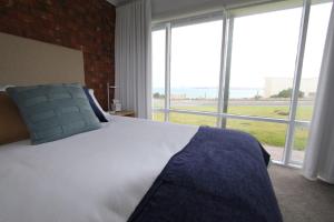 a bedroom with a large bed with a large window at Southern Sands' Beachfront Apartment in Port Elliot