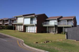 Un edificio de apartamentos con césped frente a una calle. en Southern Sands' Beachfront Apartment, en Port Elliot