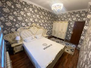 1 dormitorio con cama blanca y papel pintado con motivos florales en Квартира 3-ух Комнатная в центре города, en Ferganá