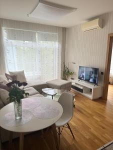 een woonkamer met een bank, een tafel en een tv bij Vaidava’s Apartment in Rīga