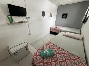 a small room with two beds and a flat screen tv at Casa da Esquina Pousada in Recife