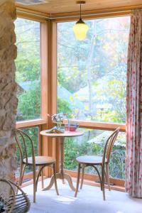 uma mesa e cadeiras num quarto com uma janela em Adelaide Hills Camellia Cottage Wifi em Crafers