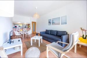 Una sala de estar con un sofá azul y una mesa. en Casa Cláudia - Cond do Mar, en Lagos