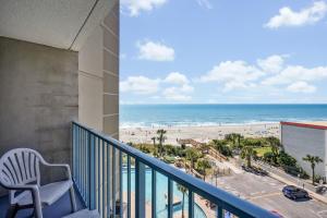 a balcony with a chair and a view of the beach at Sand Dunes Resort & Suites in Myrtle Beach