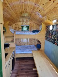 a log cabin with a bed in the middle at Woodie the shepherds hut - sleeps 4 in Chichester