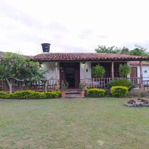 uma pequena casa branca com um alpendre e um quintal em Hostal Sueño Real Campestre em San Gil