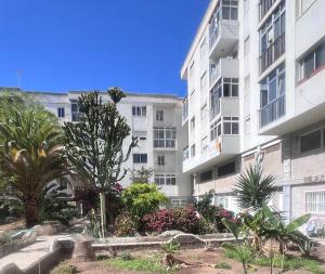 een groot wit appartementencomplex met bomen en planten bij Relax Park 1 in Las Palmas de Gran Canaria