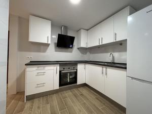 a kitchen with white cabinets and a sink and a microwave at Apartamento centro de Benalmádena in Benalmádena