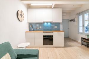 una cocina con armarios blancos y un sofá verde en Apartment Pontevedra 20m from the beach, en Barcelona