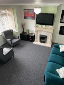 a living room with a fireplace and a television at Lovely 3 bed house with patio/bbq in Slades Green