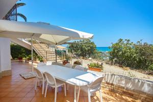 uma mesa e cadeiras com um guarda-sol e o oceano em Villa Azzurra em Castellammare del Golfo