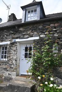 a stone house with a white door and a window at Caurel Cottage in Caurel