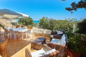 um pátio com uma mesa e cadeiras e o oceano em Villa Azzurra em Castellammare del Golfo
