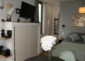 - une chambre avec un lit et un vase de fleurs blanches dans l'établissement L'Embellie, à Aix-les-Bains