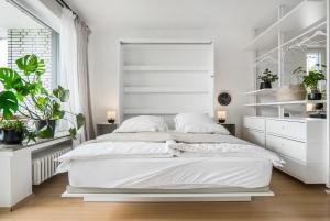 a white bedroom with a white bed and plants at Ruhiges und modernes Zuhause in Münster