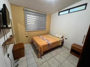 Habitación pequeña con cama y ventana en surf house en Puerto Baquerizo Moreno