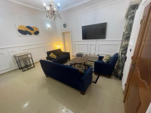 sala de estar con 2 sofás azules y TV en Tarablue appart, En plein centre-ville, Agréable & spacieux, en Libreville