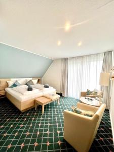 um quarto de hotel com uma cama e um sofá em Kirchspielkrug Landhotel & Restaurant em Westerhever
