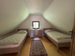 ビドミニにあるDomek Bajkaのベッド2台と鏡付きの屋根裏部屋