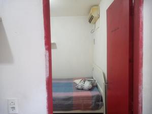 una puerta roja que conduce a un dormitorio pequeño con cama en Flat Beira-Mar do CID, en Maragogi