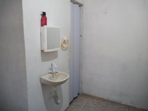 un baño con lavabo y una botella roja en la pared en Flat Beira-Mar do CID, en Maragogi