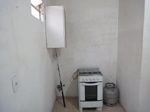 cocina con fogones y pared blanca en Flat Beira-Mar do CID, en Maragogi